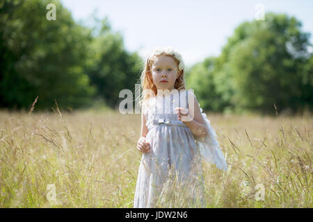 Girl wearing angel wings in field Banque D'Images