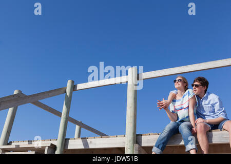 Couple sitting on boardwalk, low angle Banque D'Images