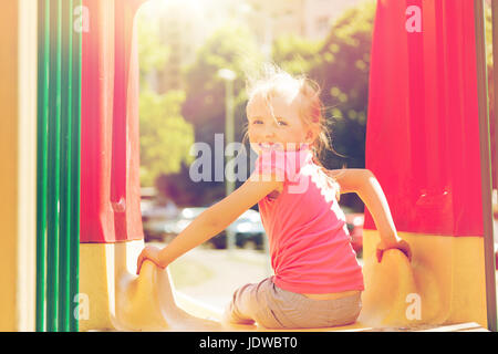Happy little girl sur la diapositive à l'aire de jeux pour enfants Banque D'Images