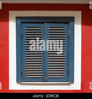 Une belle vieille fenêtre sur un mur rouge fermé avec des volets bleus. La fenêtre est photographié dans la vieille ville de Riga. Banque D'Images