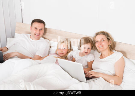 Jeune famille à l'aide d'ordinateurs portables dans les chambres à la maison Banque D'Images