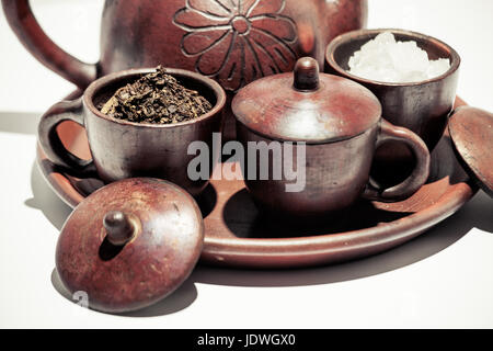 Poci pot ou pot de thé traditionnel indonésien avec des feuilles de thé séchées Ingrédients Sucre, dans de belles tasses faïence argile sur présentation d'affichage Banque D'Images