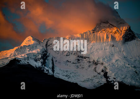 Le pic enneigé du Nevado Huandoy dans la Cordillera Blanca, lors d'un coucher du soleil orange. Photographié à partir de Yungay, Pérou. Banque D'Images