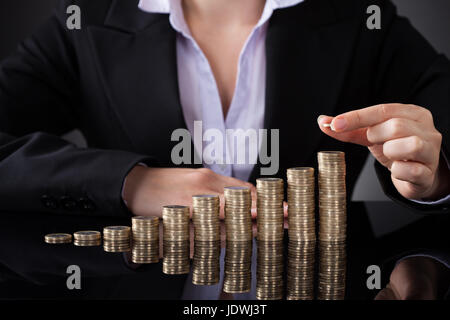 Close-up of Businesswoman Putting Coin de la hausse pile de pièces Banque D'Images