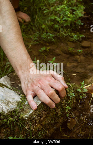 Jeune homme part touchant l'eau douce Banque D'Images