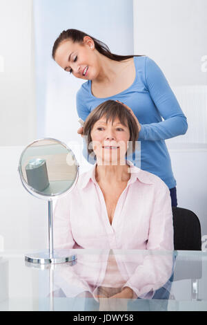 Jeune femme peignant gardien senior woman's hair at nursing home Banque D'Images