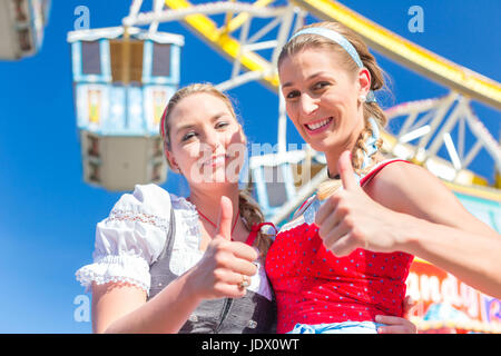 Amis visitant ensemble juste bavarois en costume national ou Dirndl en face de la grande roue Banque D'Images