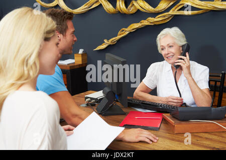 Réceptionniste Hôtel Couple aidant à vérifier dans Banque D'Images