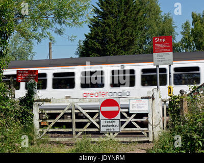 Une plus grande Anglia Train régional traversant un ancien passage à niveau avec les panneaux d'avertissement à l'est de Norwich, Norfolk, England, UK Banque D'Images