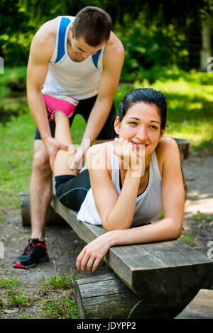 Massage homme donne de veau à jeune femme après le jogging Banque D'Images