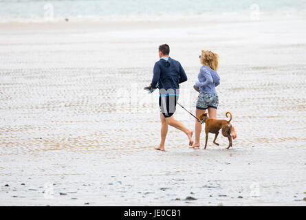 Un couple l'homme et de la femme en marche pieds nus avec leur whippet chien en laisse sur la plage de Daymer Bay Beach, Cornwall, England Uk Banque D'Images