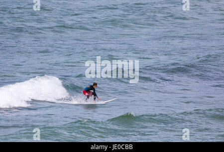 Un homme seul surfer attraper une vague à la populaire plage de surf de renommée mondiale et de Polzeath, Cornwall, England, UK Banque D'Images