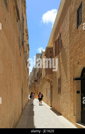 Personnes marchant rue étroite des maisons dans la cité médiévale de Mdina, Malte Banque D'Images