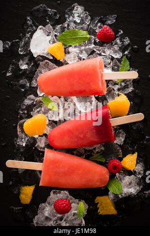 Des sucettes fruité fait de jus d'orange sanguine et de framboises. Ces frais sont un délicieux traiter sur une journée chaude. Banque D'Images