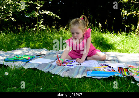 4 ans, fille, à l'extérieur à l'aide de feutres à colorier, Greatham, Hampshire, Royaume-Uni. 17 juin 2017. Banque D'Images