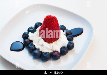 Le Dessert se compose de bleuets, fraises, crème et chocolat liquide Banque D'Images