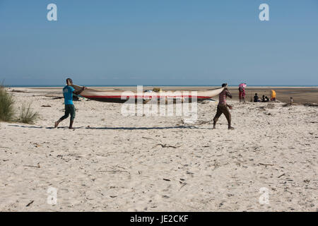 Les villageois portant leur pirogue de mer, Morondava, Madagascar Banque D'Images