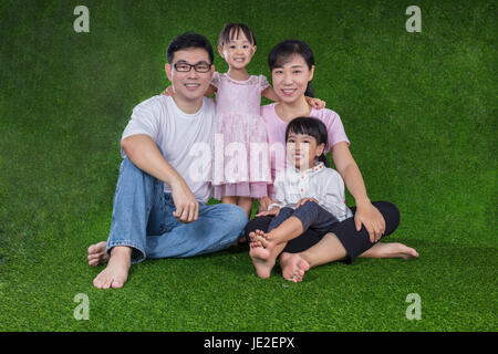 Heureux parents chinois et asiatiques filles assis sur l'herbe à l'extérieur parc Banque D'Images