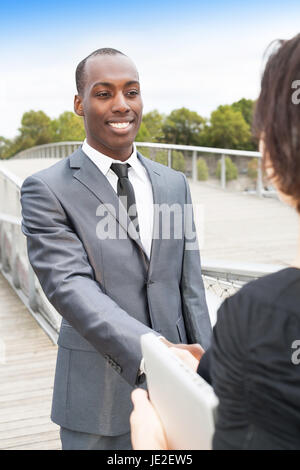 Smiling businessman and businesswoman ou client handshaking Banque D'Images