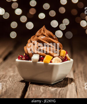 Close up Brown le yogourt glacé au-dessus de tranches de fruits sur Bol mis sur table en bois. Banque D'Images