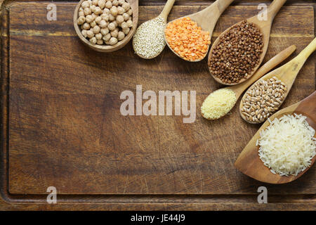 Différents types de céréales dans des cuillères en bois - le sarrasin, pois chiches, riz, quinoa, lentilles Banque D'Images