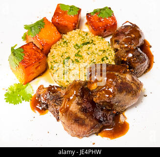 La viande biologique d'agneau cuit avec des tranches de citrouille et le quinoa dans un style oriental sur une plaque blanche Banque D'Images