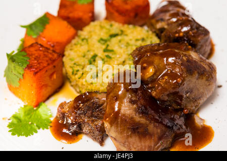 La viande biologique d'agneau cuit avec des tranches de citrouille et le quinoa dans un style oriental sur une plaque blanche Banque D'Images