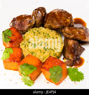 La viande biologique d'agneau cuit avec des tranches de citrouille et le quinoa dans un style oriental sur une plaque blanche Banque D'Images