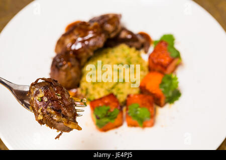 La viande biologique d'agneau cuit avec des tranches de citrouille et le quinoa dans un style oriental sur une plaque blanche Banque D'Images