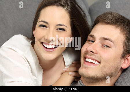 Couple heureux avec dents parfait sourire blanc et allongé sur une table et vous regarde Banque D'Images
