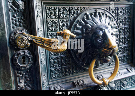 Les portes de la cathédrale de Cologne sont faits de bronze. Une tête de lion est un heurtoir et un chérubin est la poignée de porte. Banque D'Images