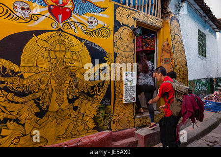 Bogota, Colombie - un touriste vérifie une liste à l'extérieur d'un magasin traditionnel dans les étroites, colorées, flâner le long de la Calle del Embudo dans la Candelaria. Banque D'Images