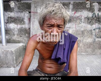 ANTIPOLO CITY, PHILIPPINES - le 14 juin 2017 : Un vieil homme avec des cheveux gris et la peau ridée pose devant l'appareil photo alors qu'il repose sur un trottoir. Banque D'Images