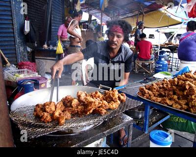 ANTIPOLO CITY, PHILIPPINES - le 14 juin 2017 : un fournisseur d'aliments de rue cuisiniers fried chicken à son magasin de fortune. Banque D'Images