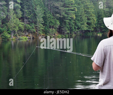 Appel de Casting ! Un pêcheur jette une ligne dans les eaux du lac calme dans l'espoir d'un en-cas ou un dîner. Banque D'Images