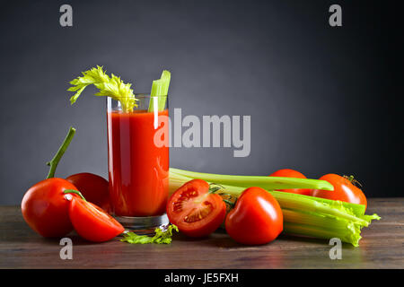 Les jus de tomates avec des tomates et du céleri sur une table en bois Banque D'Images