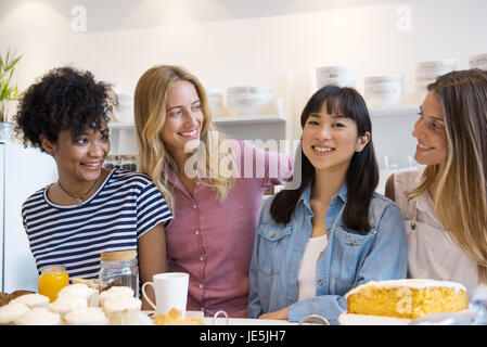 Les jeunes femmes smiling together in cafe Banque D'Images