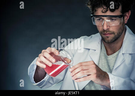 Scientist pouring liquid into test tube Banque D'Images