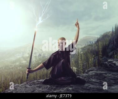 Maître de Wushu avec blade, le contrôle de la foudre sur le sommet de la montagne, les arts martiaux en homme tissu noir pose avec épée Banque D'Images