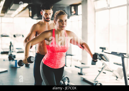 Entraîneur personnel aider jeune femme avec des exercices pour les épaules Banque D'Images