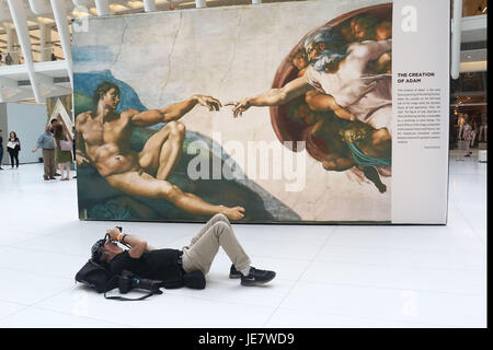 New York, New York, USA. 22 Juin, 2017. Un photographe se trouve sur le sol devant le panneau "La création d'Adam" de l'exposition Vues de près : la Chapelle Sixtine de Michel-Ange a tenu à l'Oculus à Westfield World Trade Center. L'exposition présente une expérience de qualité musée, près de-vie-taille des reproductions de l'emblématique capitaine fresques qui ornent la chapelle Sixtine à Rome. L'exposition s'exécute à travers le 23 juillet, après qu'il se rendra à 7 villes des États-Unis. Credit : Nancy/Kaszerman ZUMA Wire/Alamy Live News Banque D'Images