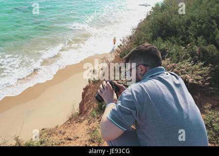 Le jeune photographe de faire des photos d'un paysage marin avec son appareil photo Banque D'Images