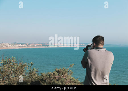 Le jeune photographe de faire des photos d'un paysage marin avec son appareil photo Banque D'Images