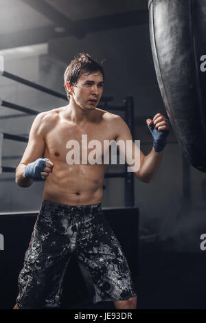 Man practicing boxing sur grand sac noir dans la salle de sport Banque D'Images