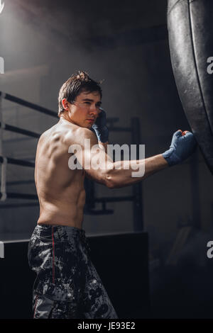 Man practicing boxing sur grand sac noir dans la salle de sport Banque D'Images