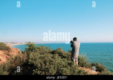 Le jeune photographe de faire des photos d'un paysage marin avec son appareil photo Banque D'Images