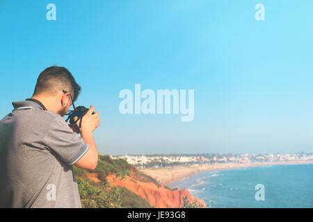 Le jeune photographe de faire des photos d'un paysage marin avec son appareil photo Banque D'Images