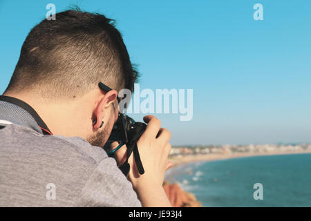 Le jeune photographe de faire des photos d'un paysage marin avec son appareil photo Banque D'Images