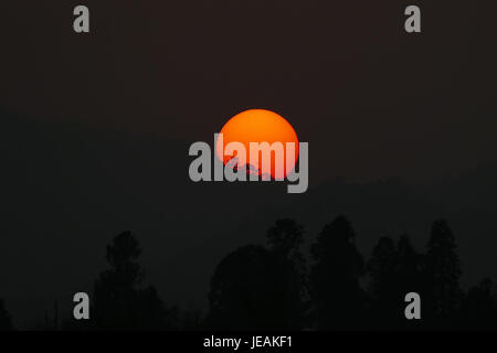 Cette image, prise le 21 novembre 2014, capture les silhouettes d'arbres contre le coucher de soleil sur le lac de l'Ouest (Xihu) à Hangzhou, en Chine. La photo met en valeur la beauté naturelle de la région, avec des taches solaires créant un effet dramatique. Banque D'Images