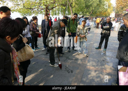 Un calligraphe à Xihu, Hangzhou, capture l'art traditionnel chinois de la calligraphie. La scène se déroule dans un environnement culturellement riche, mettant en valeur le mélange d'expression artistique et de patrimoine. Banque D'Images